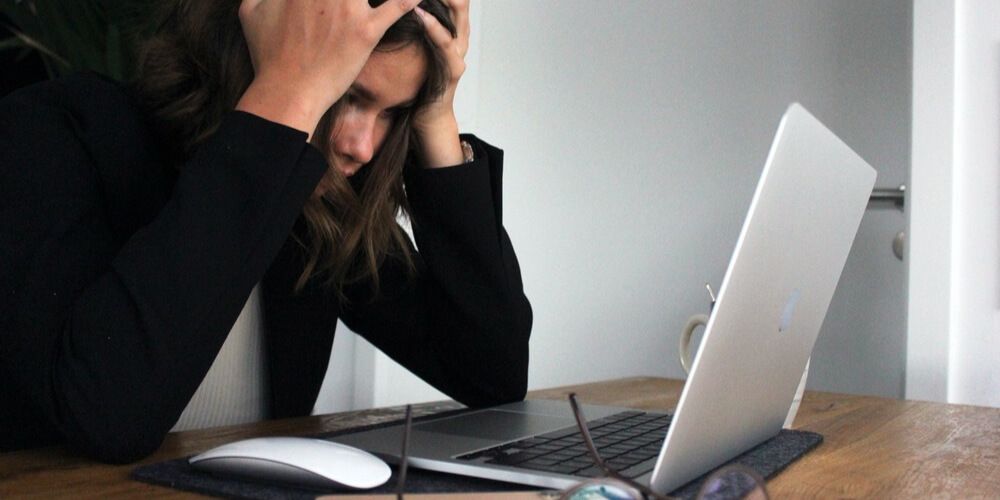 Woman holding head in frustration at laptop