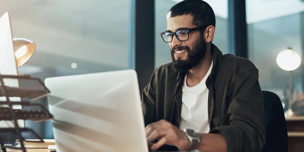 Man reading 11 money saving tips at laptop