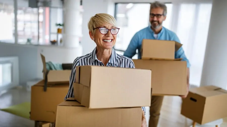 A couple is moving house and they are carrying boxes.