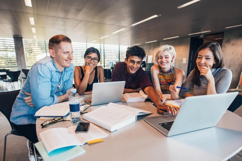 People at a desk all looking at a laptop smiling