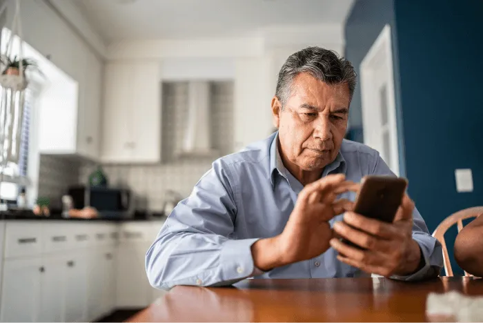 A man sitting at the table holding his phone and scrolling