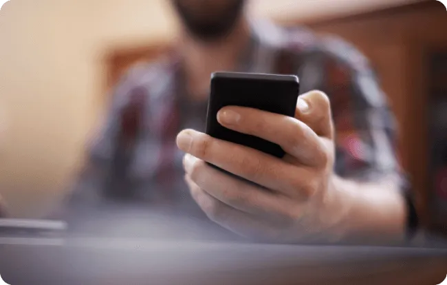 Person wearing a checked shirt holds a phone