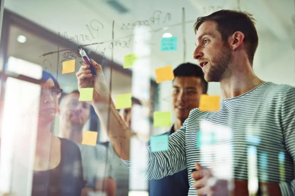 Two men are brainstorming ideas together on a whiteboard.