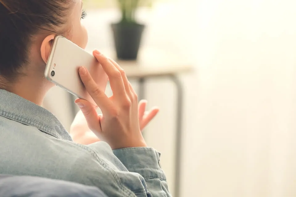 Someone speaking on the phone and making hand gestures, in a bright room