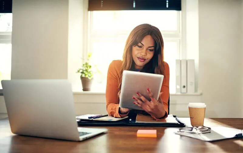 Someone sits at a desk and uses a tablet