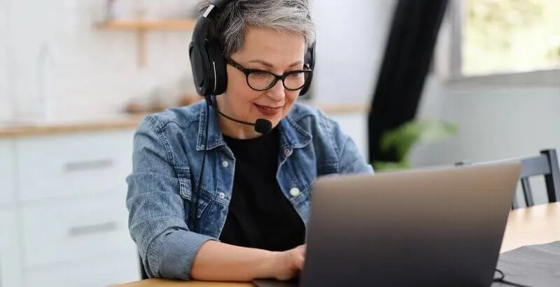 A person wearing a headset uses a laptop