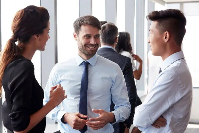 Three smartly dressed people smile and talk