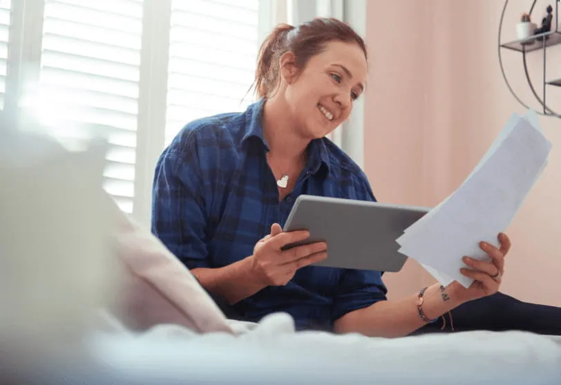 A woman sitting down looking at her application and smiling