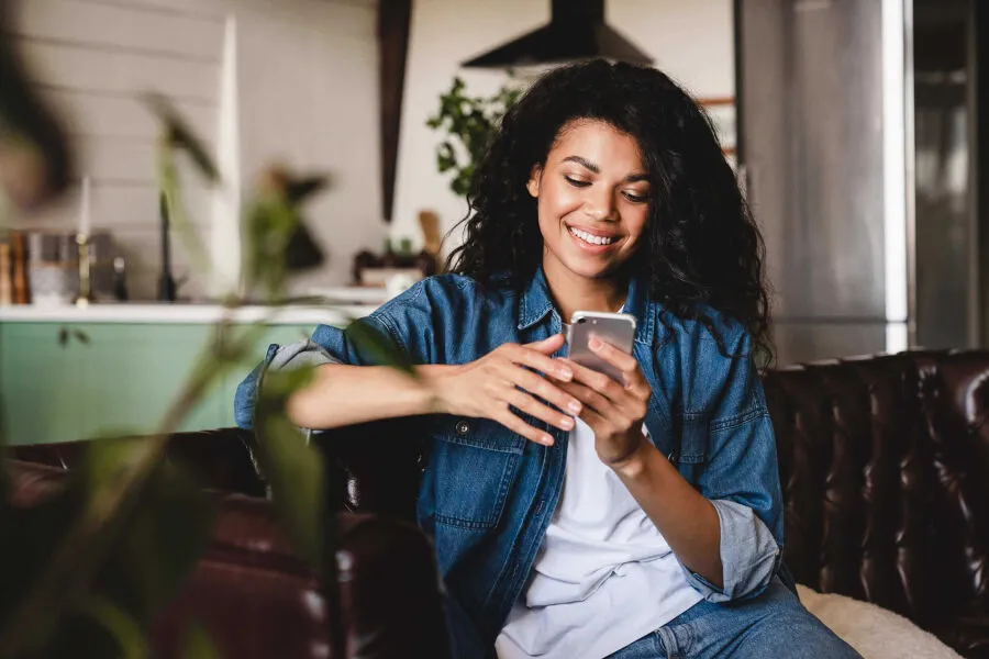 A woman is sitting on the couch and looking at her phone.