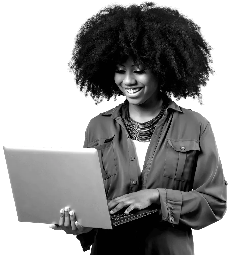 A woman standing and smiling whilst typing on her laptop