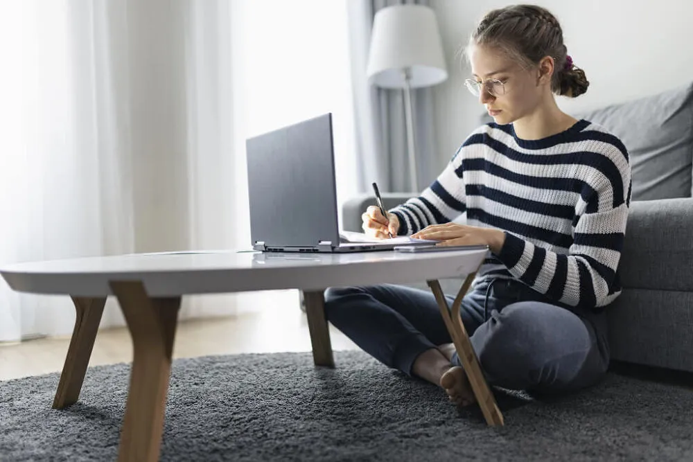 A woman working on her laptop in the living room