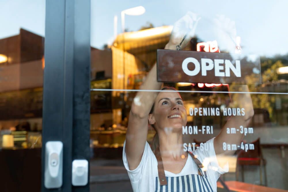 woman turning business sign to open